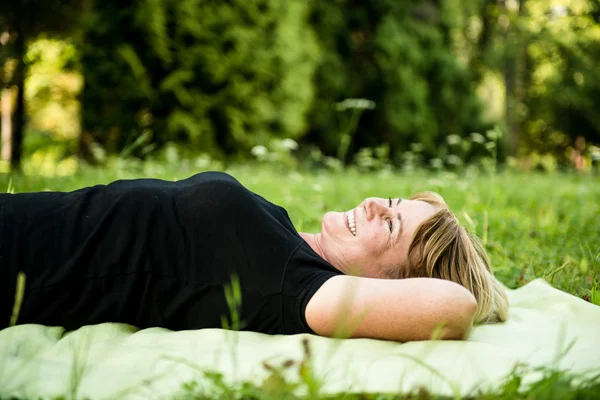 Usměvavá starší žena ležící na venkovní — Stock fotografie