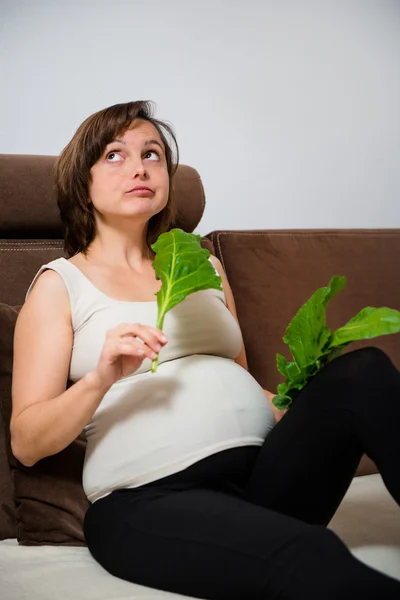 Беременная женщина ест шпинат — стоковое фото