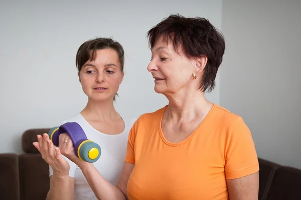 Mature woman exercising with trainer — Stock Photo, Image