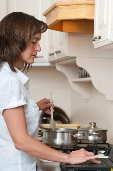 Multitasking - preparing meal and working — Stock Photo, Image