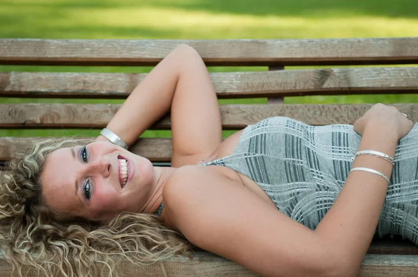 Femme souriante couchée sur le banc à l'extérieur — Photo