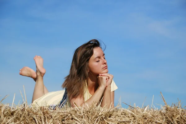 Mujer joven acostada en el heno — Foto de Stock