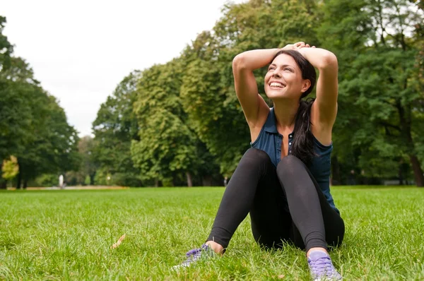 Расслабьтесь - спортсменка сидит в траве — стоковое фото