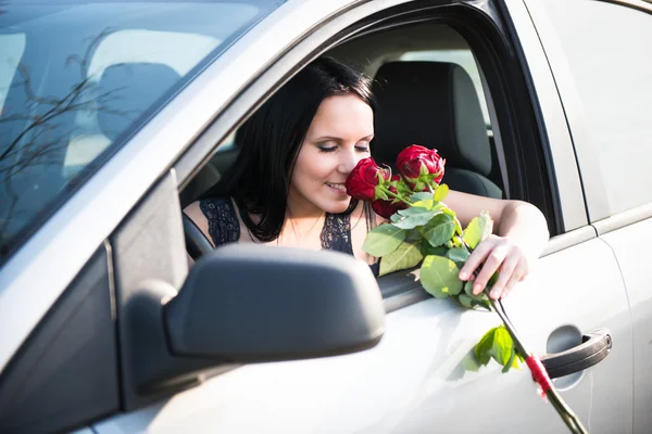 Frau mit Rosen im Auto — Stockfoto