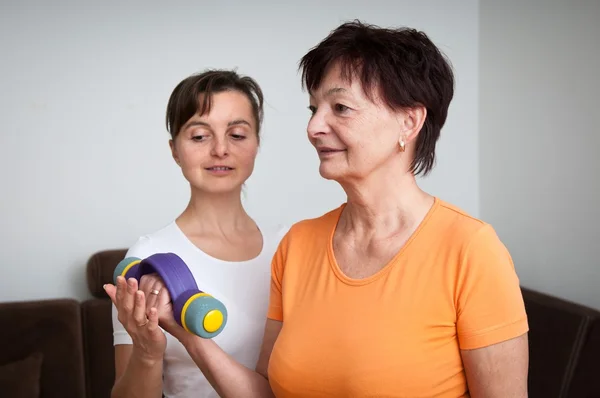 Coach assisting senior woman exercising with barbells — Stock Photo, Image