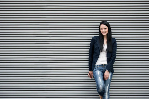 Vrouw staand bij gestreepte muur — Stockfoto