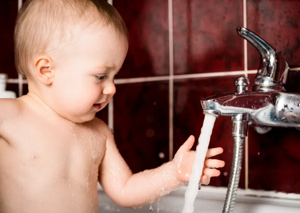 Baby playing with water faucet — Stock Photo, Image