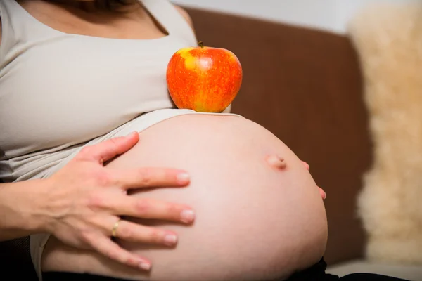 Detalhe da barriga grávida com maçã — Fotografia de Stock