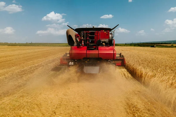 Vista aerea vista frontale della mietitrebbia raccolta grano emette nuvole di polvere e fumo. — Foto Stock