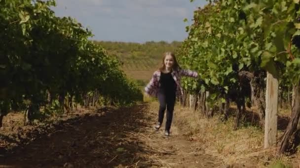 Vista frontal de uma menina feliz correndo através de fileiras de videiras — Vídeo de Stock