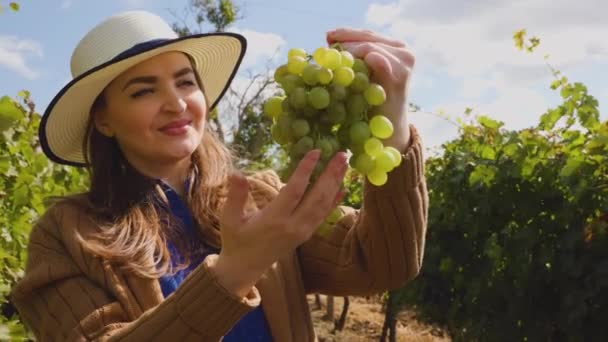 Enólogo oliendo mujer adulta con sombrero sosteniendo un ramo de uva blanca — Vídeos de Stock