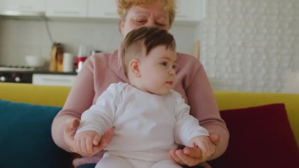 Szczęśliwa, biała babcia zabawia się i przytula swoją wnuczkę w domu. — Wideo stockowe