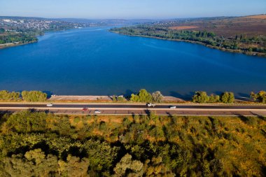  İnsansız hava aracının hareket halindeki arabaları ve banliyölerde gölü olan bir otoyolda uçuşu.