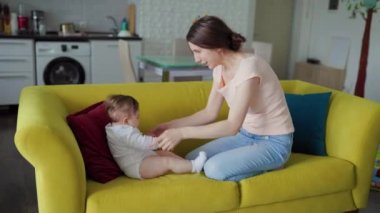 Mutlu aile sevdalısı genç anne, küçük sevimli kızıyla oynuyor.