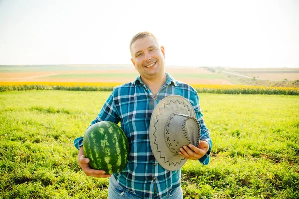 Muž farmář s melounem v ruce a dívá se na fotoaparát. — Stock fotografie