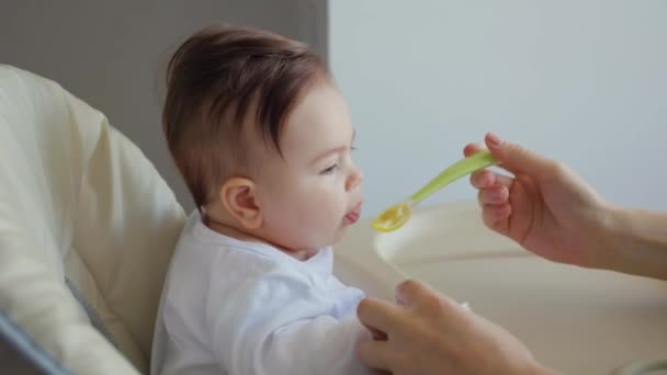 Портрет сладкого ребенка, которого кормят детским питанием с ложки — стоковое видео
