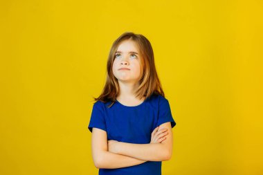 Stüdyoda elleri çapraz sarı arka planda üzgün bir çocuk.