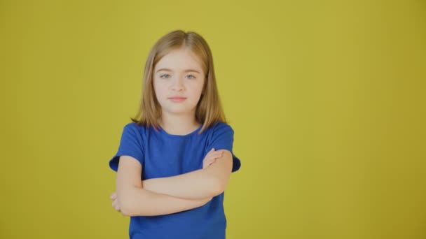 Verärgertes Kind mit gekreuzten Händen auf gelbem Hintergrund im Studio. — Stockvideo