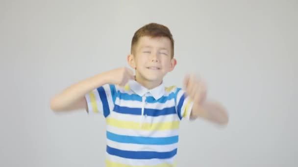 Симпатичный мальчик весело танцует в студии на белом фоне — стоковое видео