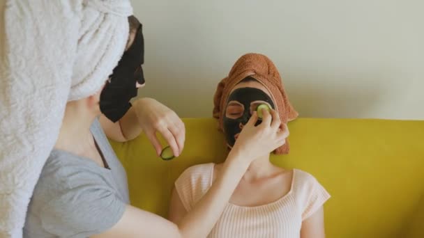 Mulher aplica fatias de pepino em seus olhos amigos. procedimentos cosméticos — Vídeo de Stock