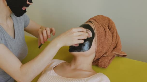 Woman applies slices of cucumber on her friends eyes — Stock Video