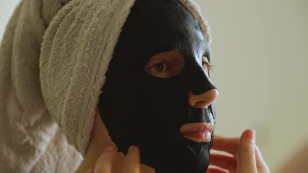 Primo piano filmato di una donna applicare carta maschera nera cura della pelle. — Video Stock