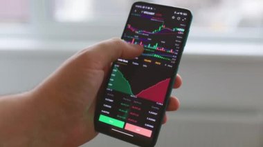 Bir akıllı telefon üzerinde borsa veri grafiği üzerinde çalışan İşadamı parmağını kapat