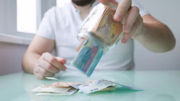 Close up of a hands of man taking money out of his glass bank — Stock Video