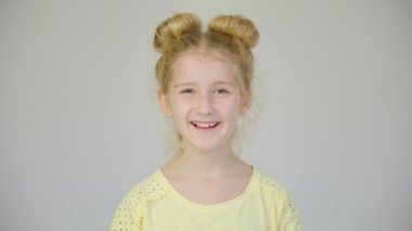 Yakışıklı ve neşeli bir kızın portresi. 4K görüntüleri küçük kızın stüdyosunda. 