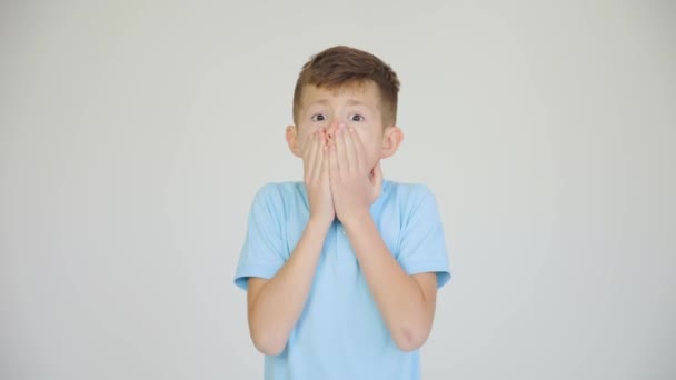 Mooie jongen gevoel verbijsterd en verbaasd kijken naar camera, witte studio achtergrond — Stockvideo
