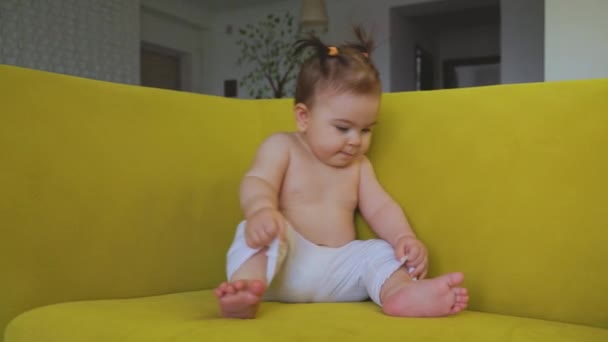 Linda niña, en el sofá amarillo en casa en la sala de estar — Vídeos de Stock