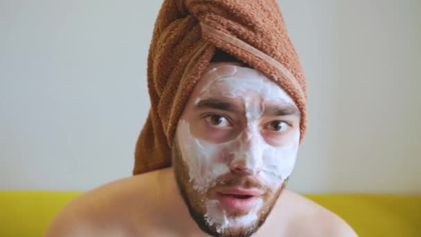Hombre barbudo divertido, con una máscara blanca en la cara posa para la cámara — Vídeo de stock