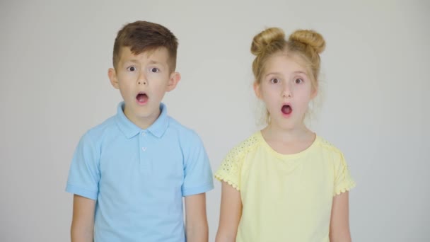 Espanto sincero. dois filhos Bonito menino e menina com os olhos bem abertos chocado e boca aberta — Vídeo de Stock