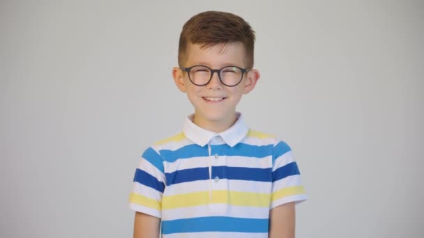 Портрет веселого мальчика в очках улыбается перед камерой. — стоковое видео