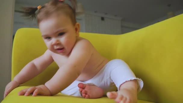 El retrato de la niña jugando en el sofá amarillo en casa en la sala de estar — Vídeos de Stock