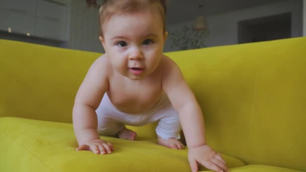 Schattig baby meisje, op de gele bank thuis in de woonkamer — Stockvideo