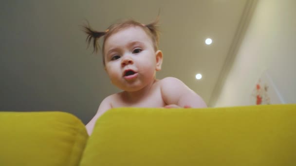 Schattig klein meisje op de gele sofa het maken van eerste stappen thuis — Stockvideo