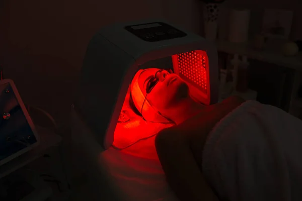 Kadın güzellik salonunda morötesi LED ışık tedavisi görüyor.