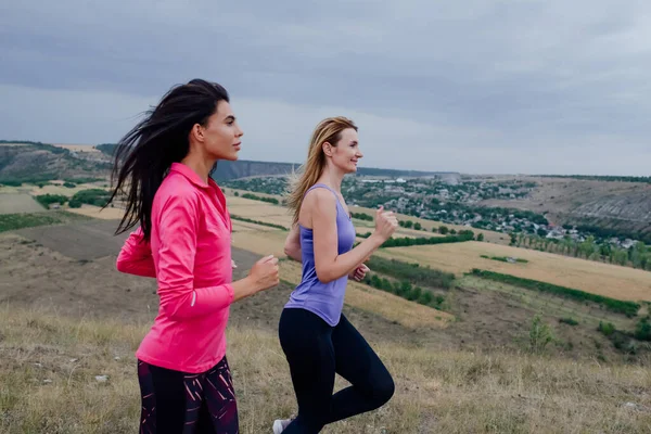 Yaz parkında iki genç kadın koşucu eğitimi. Spor salonundaki kadın dışarıda koşuyor.. — Stok fotoğraf