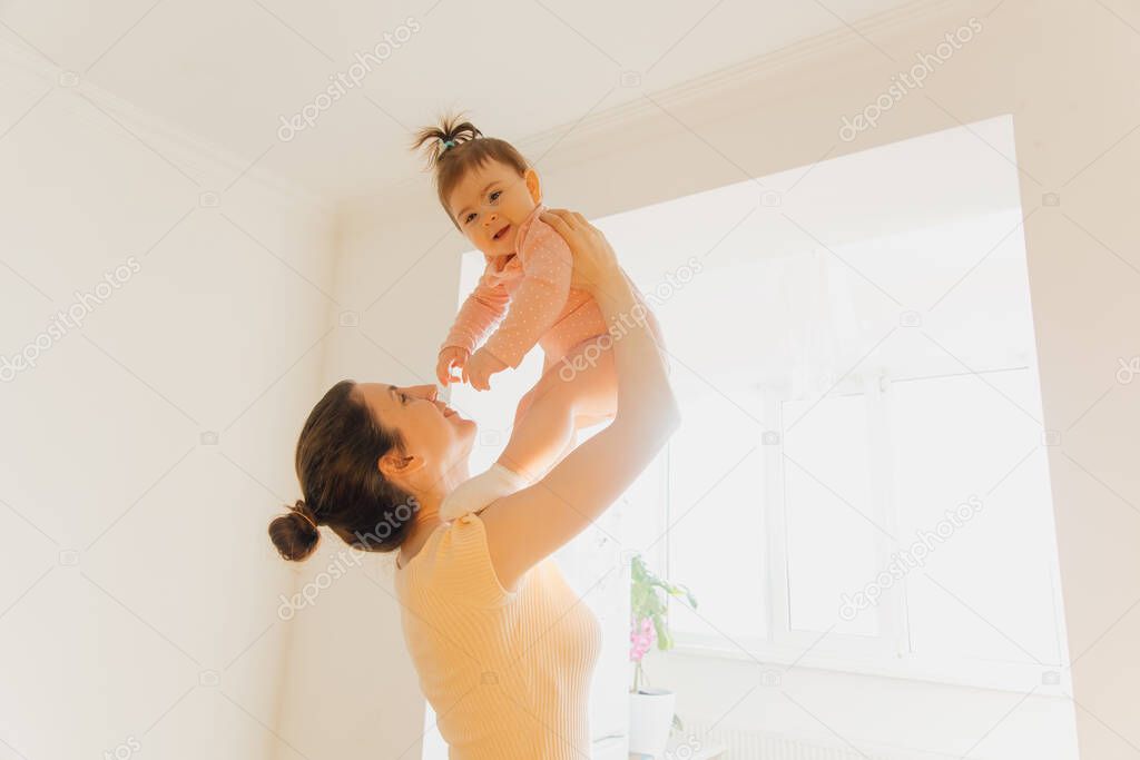 a cute baby girl is happy benevolent playing with her mother holding her in her arms