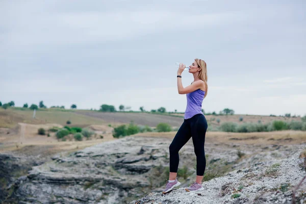 Spor sonrası su içen kadın. gökyüzü arka planında. — Stok fotoğraf