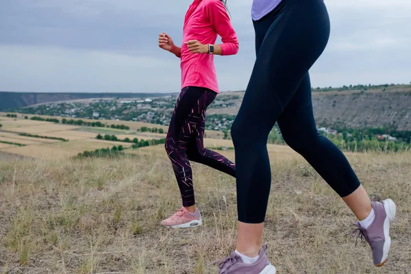 Close up, duas mulheres jovens estão se exercitando com corrida ao ar livre Quando o sol se põe no verão, — Fotografia de Stock