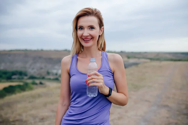 Elinde su şişesi olan çekici bir kadın. Spor yaşam tarzı. — Stok fotoğraf