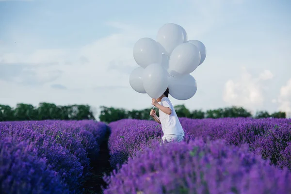 Child little boy in a field of lavender with white balloons, — Stock Photo, Image