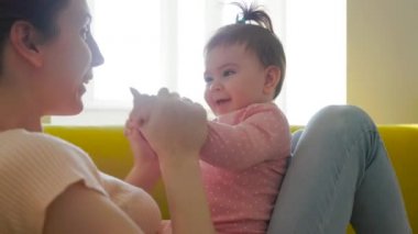 Sevgi dolu bir aile. Annem bebeğiyle kanepede oynuyor.. 