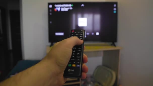 Close up dari tangan mans memilih saluran tv internet dengan remote control. — Stok Video