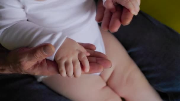 Zbliżenie pomarszczonej dłoni dziadka w wieku 50 lat i małych dłoni dziecka. — Wideo stockowe