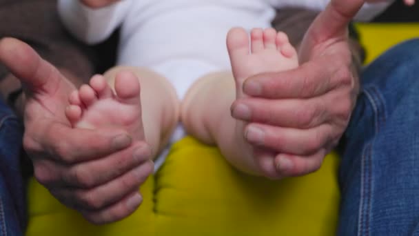 Зблизька дідові руки, тримаючи немовлят за ноги бавляться з новонародженим. — стокове відео