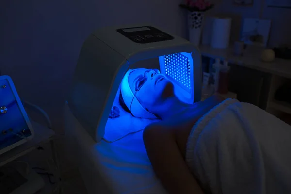 Kadın güzellik salonunda morötesi LED ışık tedavisi görüyor.