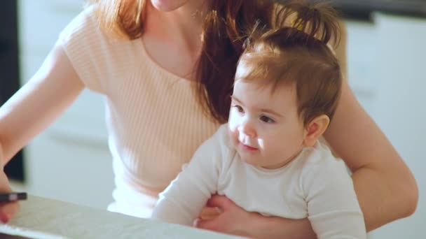 Vue rapprochée du bébé assis sur les genoux de sa mère. — Video